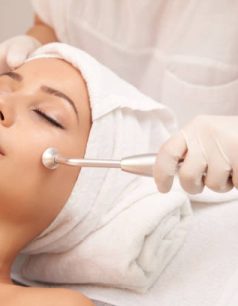 Cosmetologist using microdermabrasion machine for peeling, view from above